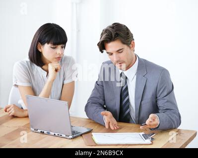 Zusammen wichtige Statistiken durchgehen. Zwei junge Führungskräfte treffen sich im Büro. Stockfoto