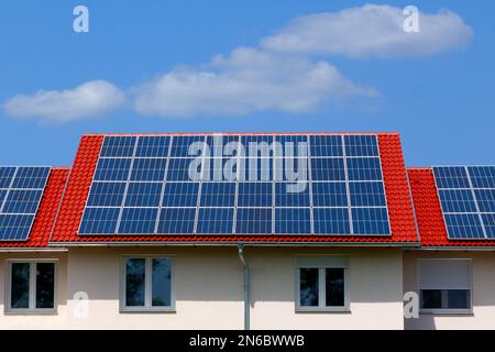 Solarpaneele für Photovoltaik-Sonnenkollektoren auf geneigtem Tonhausdach. Blauer Himmel und weiße Wolken. Alternative Energie. Umweltschutz. Außerhalb des Netzes. Stockfoto