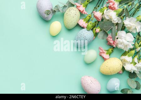 Osterfarbene Eier und ein Strauß weißer und rosafarbener Nelken mit Eukalyptuszweigen auf einem weichen grünen Hintergrund. Festlicher Hintergrund. Stockfoto