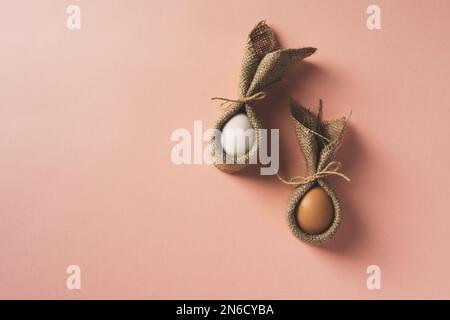 Osterhasen aus Eiern und Servietten auf pinkfarbenem Hintergrund. Draufsicht. Stockfoto