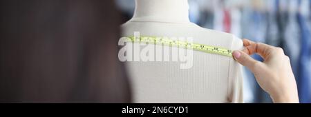 Modedesignerin Stylistin nimmt Messungen mit Zentimeter von Kleidung auf Schaufensterpuppe Stockfoto