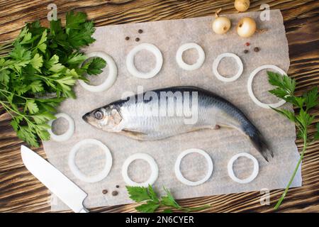 Gesalzener Hering mit Zwiebeln und Petersilie auf altem Holzhintergrund. Frischer Heringsfisch. Platz für Text kopieren. Stockfoto