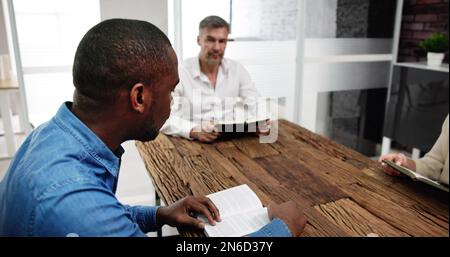 Junge, Multiethnische Menschen, Die Über Dem Holzschreibtisch Bibel Lesen Stockfoto