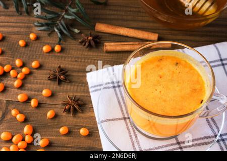 Vitaminischer, gesunder Seedorn-Tee mit frischen rohen Seedorn-Beeren, mit Honig und Zimtsticks, horizontale Ansicht. Tee aus Seebornsteinberrie Stockfoto