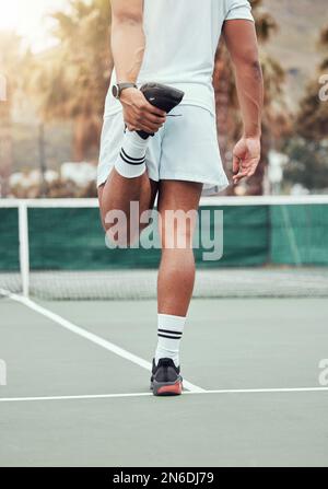 Rückansicht eines unbekannten indischen Tennisspielers, der sich Beine streckt und sich auf das Spiel vorbereitet. Ein Athlet mit ethnischer Passform, der allein steht und sich dehnt Stockfoto