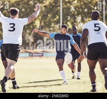 Mixed Race Rugby-Spieler, der während eines Rugby-Spiels draußen auf dem Spielfeld einen dropkick versucht. Hispanischer Mann tritt wegen Berührung oder versucht, drei Punkte zu erzielen Stockfoto