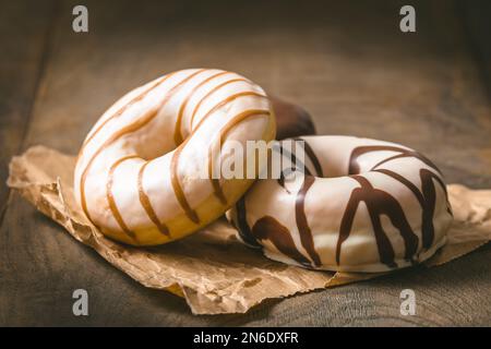 Weiße und dunkle Schokoladen-Donuts auf einem dunklen Holztisch, Kopierbereich Stockfoto