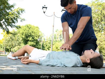 Ein Mann, der im Freien eine bewusstlose junge Frau wiederbelebt. Erste Hilfe Stockfoto