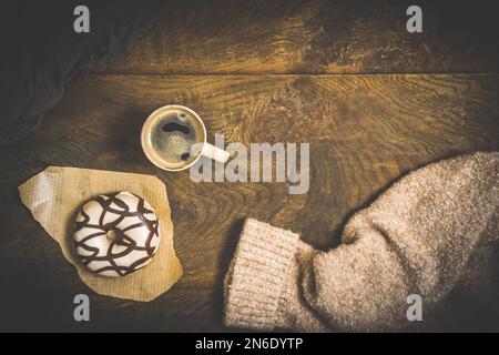 Schokoladen-Donuts und Kaffee auf einem dunklen Holztisch, gemütliche Szene einer Kaffeepause, Blick von oben Stockfoto