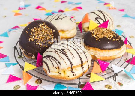 traditionelles deutsches Berliner Gebäck mit dunkel-weißer Schokolade und sprödem Haselnuss, dekoriert für Party oder Karneval Stockfoto