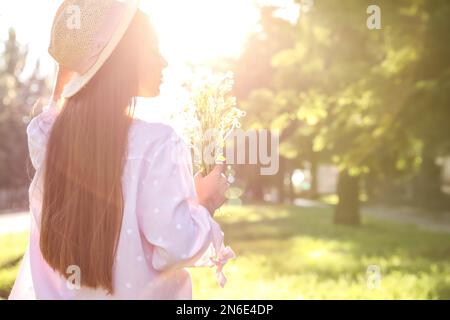 Junge Frau mit wunderschönem Blumenstrauß im Freien an sonnigen Tagen, Platz für Text Stockfoto