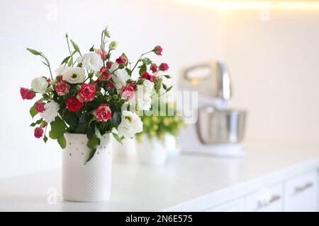 Vase mit wunderschönen Blumen auf weißer Arbeitsfläche in der Küche, Platz für Text Stockfoto