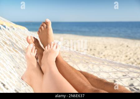 Ein Paar, das sich in der Hängematte am Strand entspannt hat Stockfoto