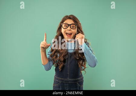 Begeistert inspiriert mit Idee Kind mit lockigen Haaren halten Partei Accessoire der Brille, Inspiration Stockfoto
