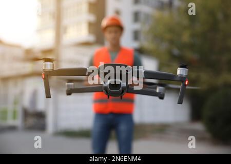 Bauarbeiter, die Drohne mit Fernsteuerung auf der Baustelle bedienen. Luftaufnahmen Stockfoto
