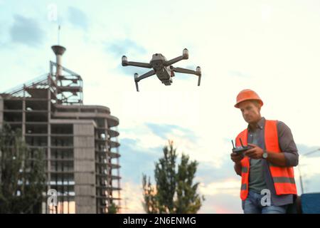 Bauarbeiter, die Drohne mit Fernsteuerung auf der Baustelle bedienen. Luftaufnahmen Stockfoto