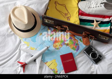 Koffer und Reiseaccessoires auf weißem Stoff, oben. Sommerferien Stockfoto