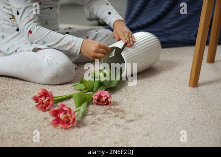 Kind und zerbrochene Keramikvase auf dem Boden zu Hause, Nahaufnahme Stockfoto