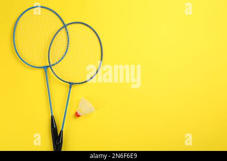 Schläger und Shuttle auf gelbem Hintergrund, flach liegend mit Platz für Text. Badminton-Ausrüstung Stockfoto