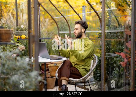 Mann arbeitet ferngesteuert auf Laptop im Garten Stockfoto