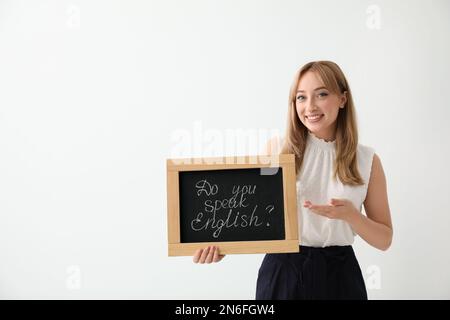 Junge Lehrerin mit Tafel und Wörtern Sprechen sie Englisch? Auf hellem Hintergrund. Platz für Text Stockfoto