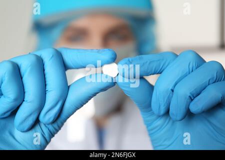 Wissenschaftler in Schutzhandschuhen, die Pillen halten, Nahaufnahme Stockfoto