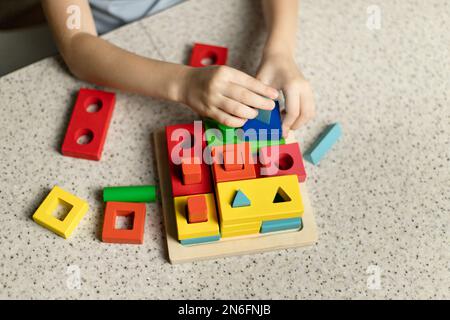 Ein Kind spielt ein pädagogisches Puzzle aus umweltfreundlichem Holz Stockfoto