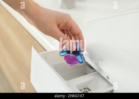 Frau, die Waschmittelkapsel in die Waschmaschine steckt, Nahaufnahme Stockfoto