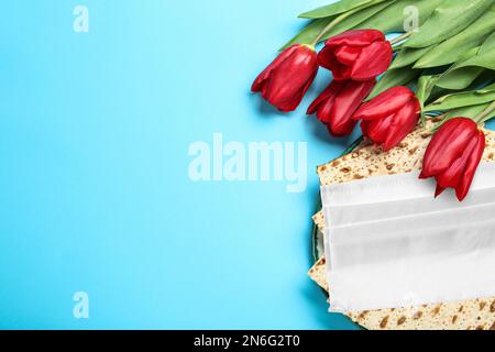 Coronavirus-Pandemie. Flache Laienzusammensetzung mit Passover-Matten und Gesichtsschutzmaske auf blauem Hintergrund Stockfoto