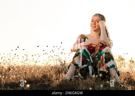 Frau mit Vitiligo, die in die Kamera schaut und lächelt, während sie sich in der Natur entspannt. Stockfoto