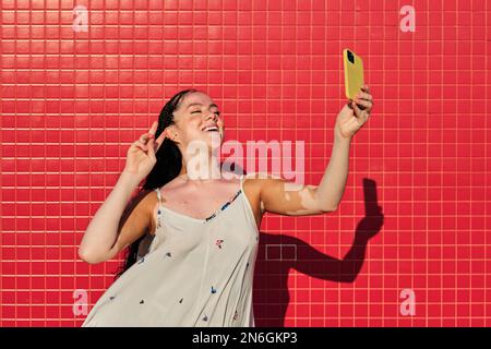 Frau mit Vitiligo, die im Freien lächelt, während sie Selfies mit einem Mobiltelefon macht. Stockfoto