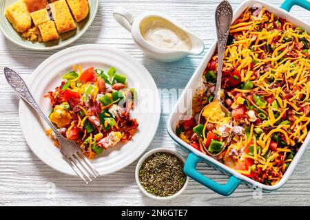 pinto Beans Speck Maisbrotsalat mit Tomaten, Paprika, Mais und Cheddar Käse in rechteckiger Schüssel und eine Portion auf dem Teller mit weißem Holz, hori Stockfoto