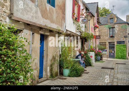 Blick auf eine typisch südfranzösische Altstadtgasse mit Blumenladen und einem Mann mit Strohhut davor. Mediterranes Flair im historischen Stil Stockfoto