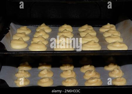 Französische Käsepuffs. Französisches Gebäck Gougeres auf einem Backblech im Ofen vor dem Backen Stockfoto