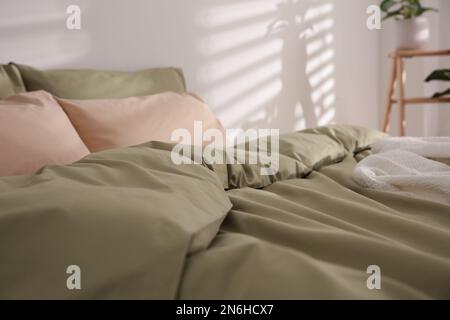 Großes Bett mit weicher Decke drinnen, Nahaufnahme Stockfoto