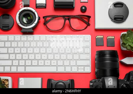 Flache Laienzusammensetzung mit Kamera- und Videoproduktionsausrüstung auf rotem Hintergrund Stockfoto