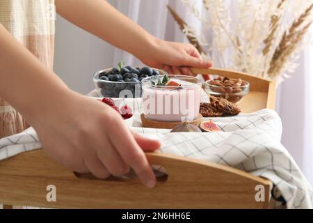 Eine Frau hielt ein Holztablett mit köstlichem Frühstück und FeigenSmoothie, Nahaufnahme Stockfoto