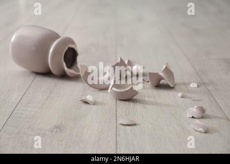 Zerbrochene rosafarbene Keramikvase auf Holzboden Stockfoto