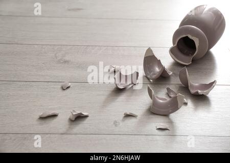 Zerbrochene rosafarbene Keramikvase auf Holzboden Stockfoto