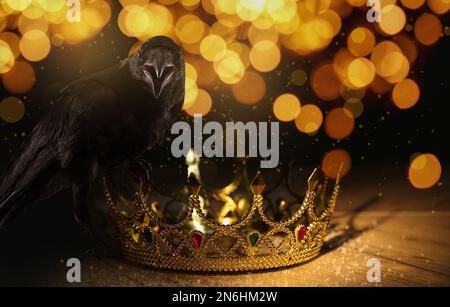 Fantasiewelt. Schwarze Krähe auf goldener Krone, Bokeh-Effekt Stockfoto