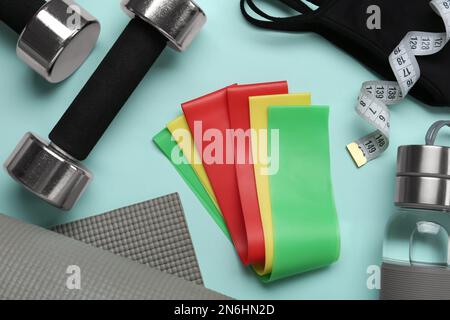 Flache Laienzusammensetzung mit Fitness-Elastikbändern auf hellblauem Hintergrund Stockfoto
