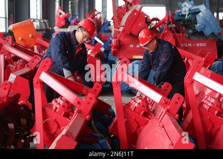 LIANYUNGANG, CHINA - 10. FEBRUAR 2023 - Arbeiter montieren landwirtschaftliche Maschinen bei einem Landmaschinenunternehmen in Lianyungang City, Ostchina“ Stockfoto