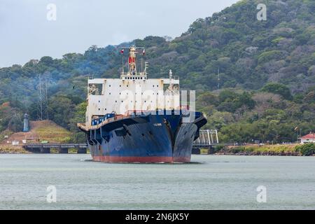 El Yunque, ein Containerschiff, bewegt sich in den schmalen Culebra-Schnitt bei Gamboa im Panamakanal. Die Gamboa-Brücke befindet sich auf der rechten Seite. Panama. Stockfoto