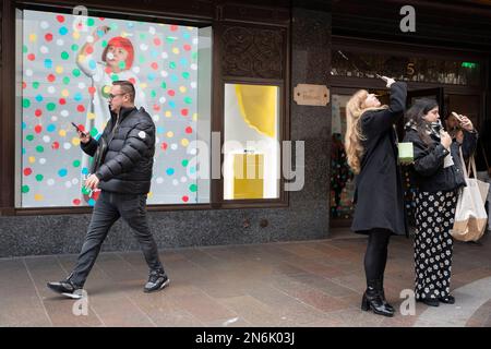 Die Öffentlichkeit interagiert am 9. Februar 2023 in London in einem Fenster von Harrods in Knightsbridge mit einer Leinwand, auf der der Künstler Yayoi Kusama zu sehen ist. Der unverkennbare Künstler Yayoi Kusama arbeitet mit Louis Vuitton zusammen, und ihre Zusammenarbeit zeigt sich derzeit in den Fenstern vieler Einzelhändler, die die französische Luxusmarke für Gepäck und Handtaschen auf Lager haben. Stockfoto