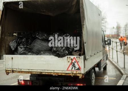 Müllsäcke hinten im Auto. Abfalltransport in schwarzen Säcken. Transport zur Müllabfuhr. Stockfoto