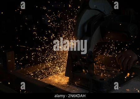 Funken aus Metall. Viele Funken aus Schleifstahl. Kreissäge schneidet Metall. Stockfoto