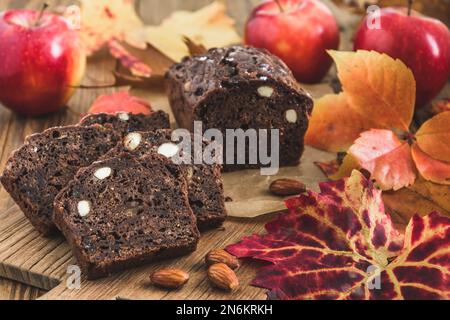 Herbstkuchen oder weihnachtskuchen mit Äpfeln auf einem Holzbrett, verziert mit farbigen Blättern Stockfoto