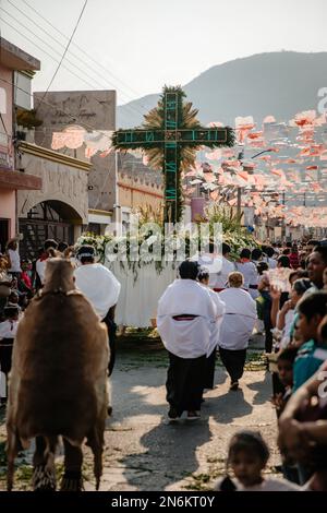 Menschen in religiösen Gewändern tragen ein riesiges Kreuz während der jährlichen Tanzparade für die Stadt Stockfoto