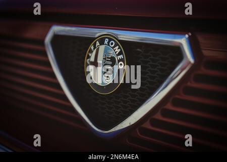 Eine Makroaufnahme des Logos eines roten Alfa Romeo 75 Retro-Sportwagens Stockfoto