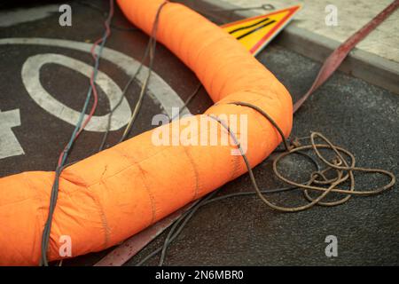 Kanalisationsreparatur. Orangefarbenes Rohr. Details zu den Arbeiten in der Stadt. Reparatur der Infrastruktur. Stockfoto